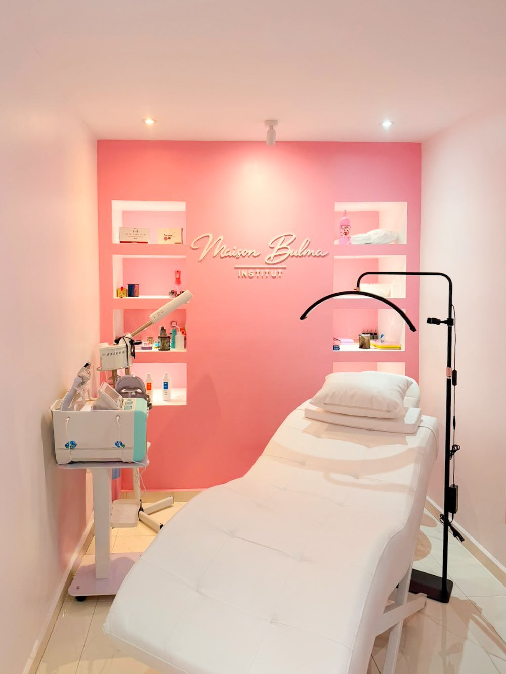La cabine de soin du visage, mur rose et table de soin blanche